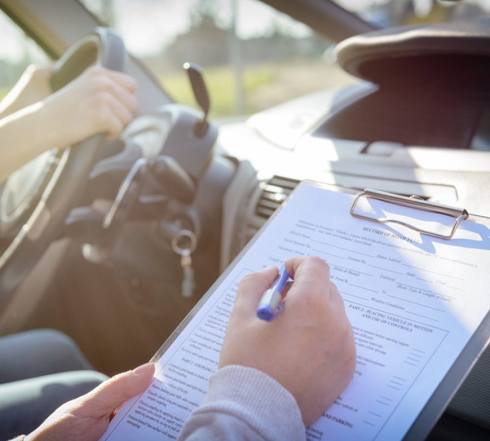 Examiner,Filling,In,Driver's,License,Road,Test,Form,Sitting,With